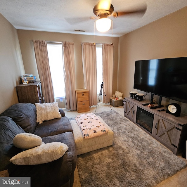 living room with visible vents, a ceiling fan, and carpet