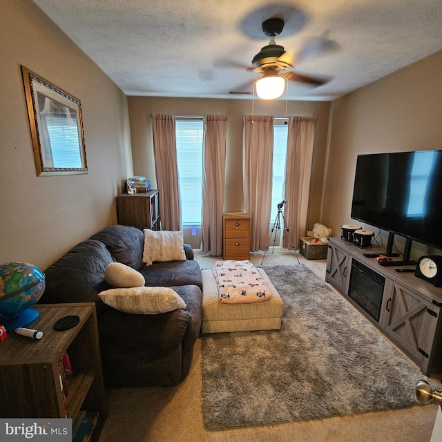 living area with carpet floors, ceiling fan, and a textured ceiling