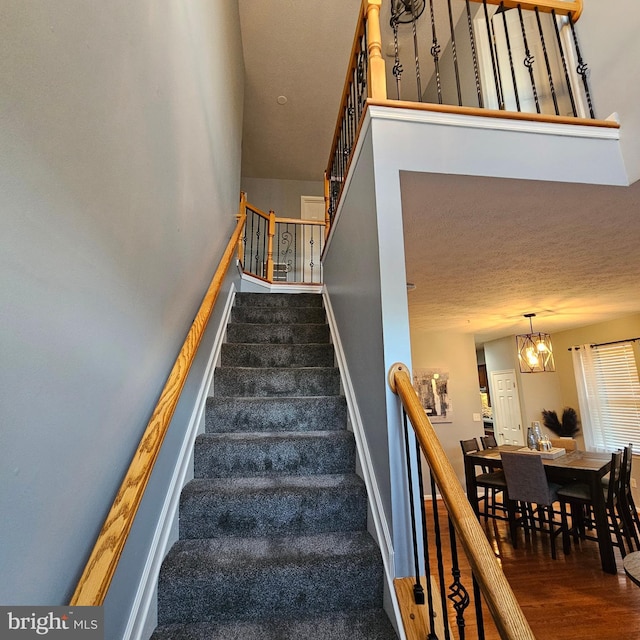 stairway featuring baseboards, an inviting chandelier, and wood finished floors