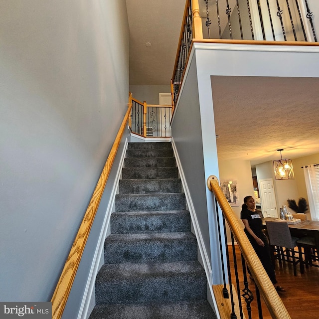 staircase with a chandelier and wood finished floors