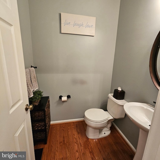 bathroom with baseboards, toilet, and wood finished floors
