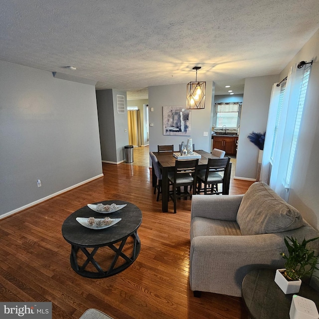 living area with a textured ceiling, wood finished floors, and baseboards