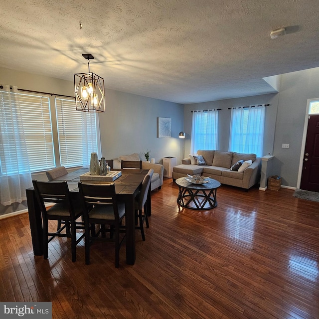 dining room with dark wood-type flooring, a textured ceiling, and a chandelier