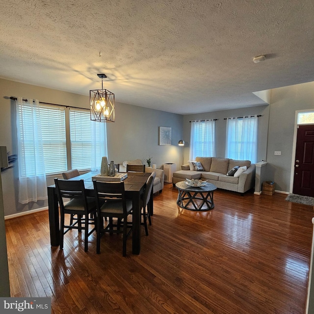 dining room featuring dark wood-style flooring, baseboards, an inviting chandelier, and a textured ceiling