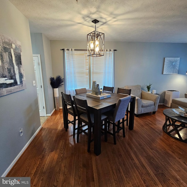 dining room featuring baseboards, a chandelier, hardwood / wood-style flooring, and a textured ceiling