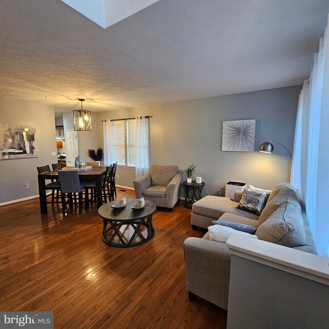living room with a textured ceiling, wood-type flooring, and baseboards