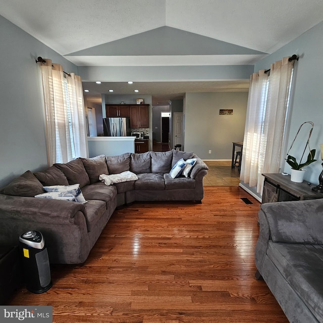living room with baseboards, wood finished floors, and lofted ceiling