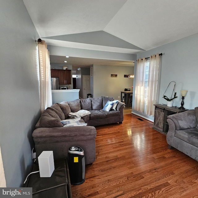 living area with visible vents, wood finished floors, and lofted ceiling