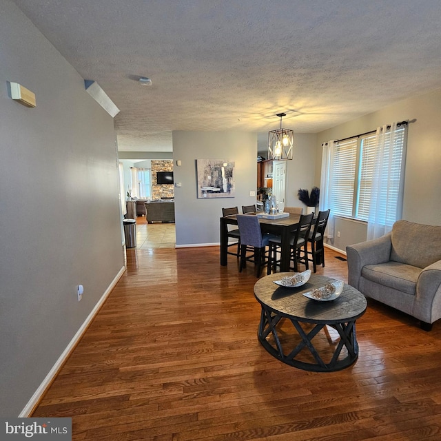 living room with a chandelier, a textured ceiling, wood finished floors, and baseboards
