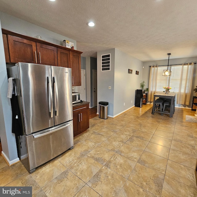 kitchen featuring a textured ceiling, appliances with stainless steel finishes, baseboards, and dark countertops
