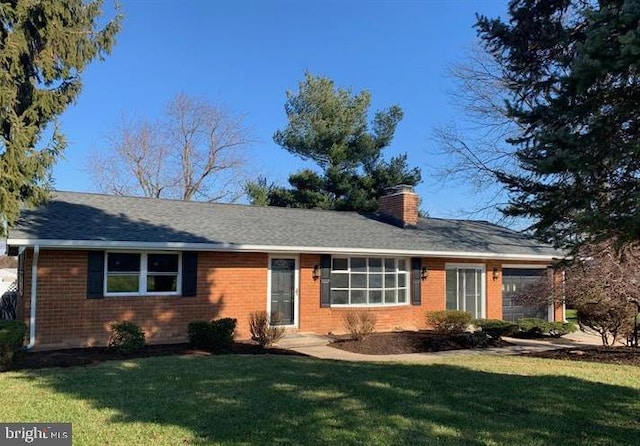 ranch-style home with a chimney, a front lawn, and brick siding