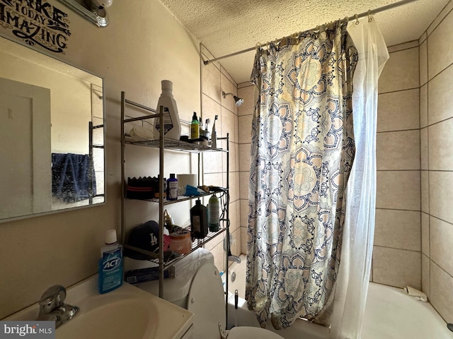 full bath featuring a textured ceiling, a sink, toilet, and shower / tub combo