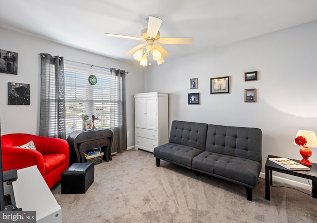 carpeted living room with baseboards and a ceiling fan
