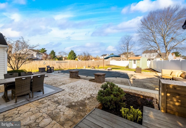 view of patio / terrace featuring a shed, a fenced backyard, outdoor dining area, and an outdoor structure