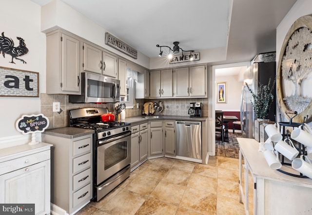 kitchen featuring tasteful backsplash, light tile patterned flooring, dark countertops, a sink, and stainless steel appliances