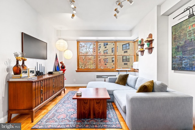 living area with radiator, baseboards, and rail lighting