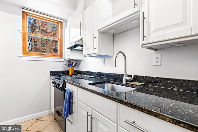 kitchen featuring white cabinets, a sink, black gas range, dark stone counters, and light tile patterned flooring