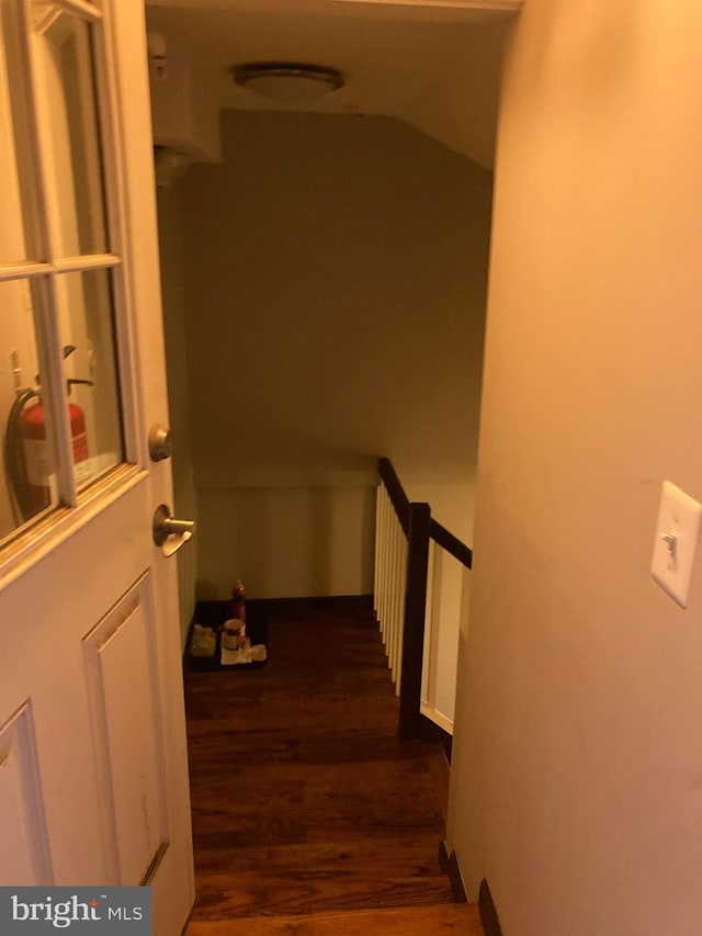 corridor with dark wood-style floors and vaulted ceiling