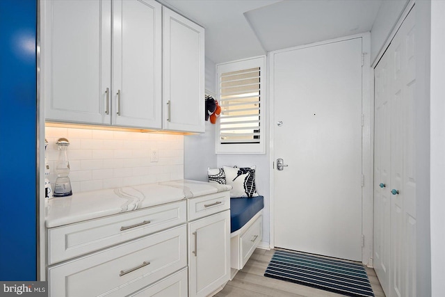 8500 Coastal Hwy Unit 805, Ocean City, MD 21842 - interior space with white cabinets, decorative backsplash, light wood-type flooring, and light stone counters