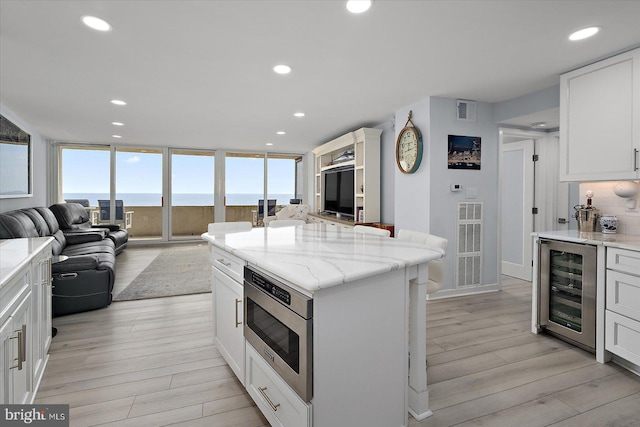 8500 Coastal Hwy Unit 805, Ocean City, MD 21842 - kitchen featuring stainless steel microwave, open floor plan, visible vents, light wood-style floors, and beverage cooler