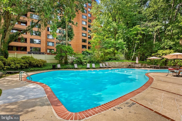 community pool with a patio area and fence