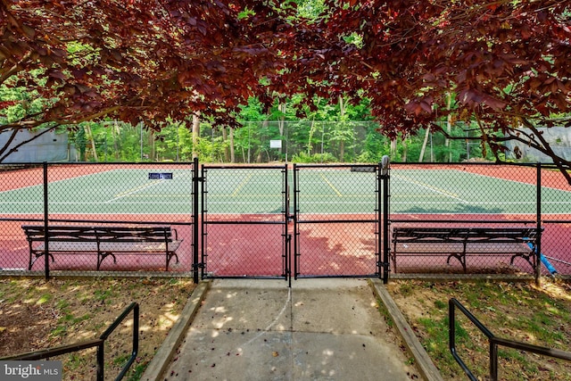 view of tennis court with a gate and fence