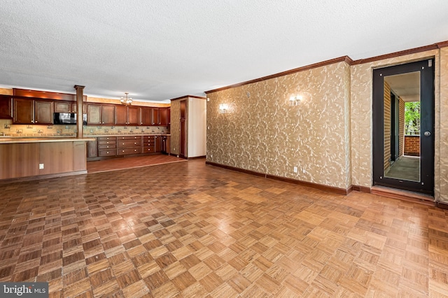 unfurnished living room with baseboards, a textured ceiling, and crown molding