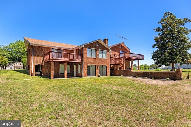 back of house featuring a wooden deck, brick siding, a lawn, and a chimney