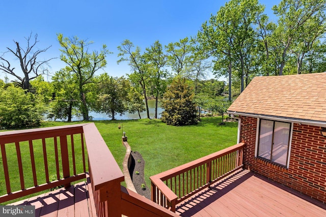 wooden terrace with a water view, a lawn, and view of wooded area