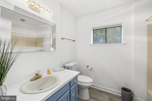 bathroom featuring wood finished floors, a shower, toilet, vanity, and baseboards