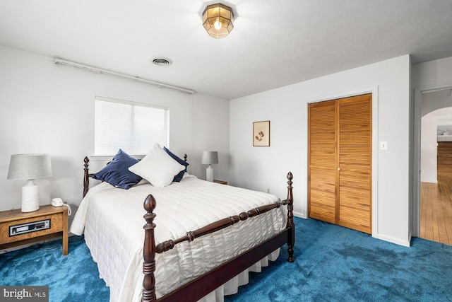 carpeted bedroom featuring a closet, arched walkways, and baseboards