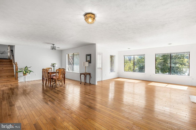 living room featuring plenty of natural light, a textured ceiling, stairway, wood-type flooring, and baseboards