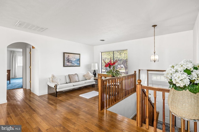 hallway with arched walkways, an upstairs landing, wood-type flooring, and baseboards