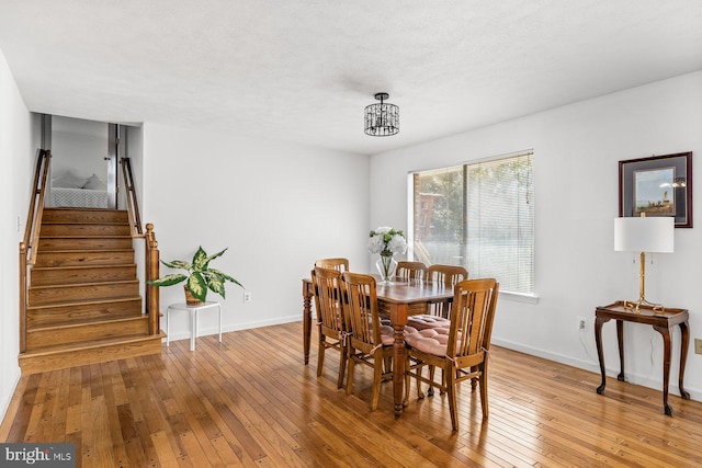 dining room featuring light wood-style flooring, stairway, and baseboards