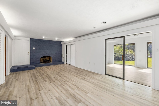 unfurnished living room featuring light wood-style flooring, a brick fireplace, and baseboards