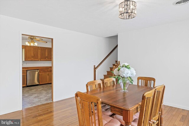 dining area featuring light wood-type flooring, stairs, a chandelier, and baseboards