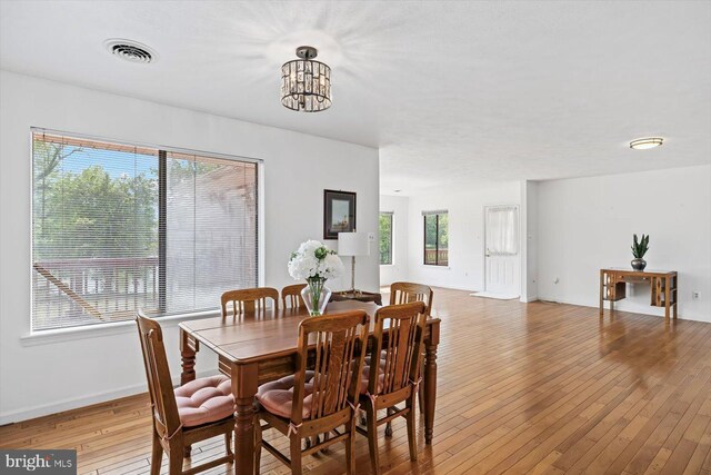 dining room with light wood-type flooring, a chandelier, and baseboards