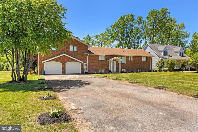view of front of house with asphalt driveway, a front yard, brick siding, and an attached garage
