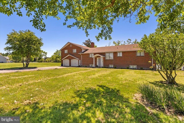 view of front of property with a garage, driveway, brick siding, and a front yard