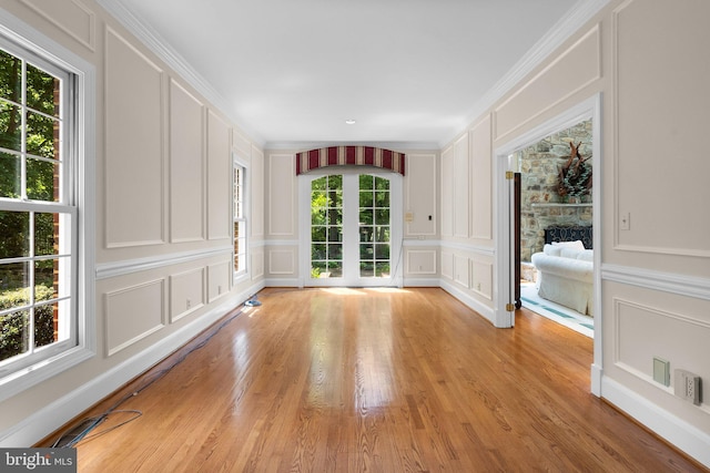 interior space featuring a decorative wall, light wood-type flooring, a stone fireplace, and visible vents