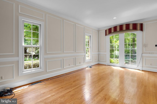 unfurnished room with crown molding, a decorative wall, and wood finished floors