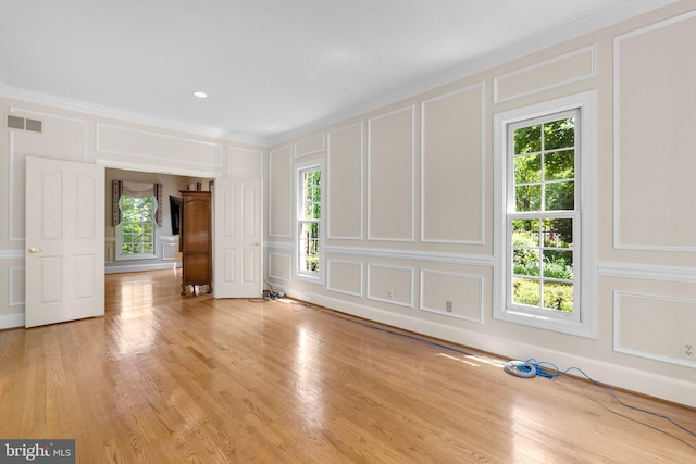 unfurnished room featuring plenty of natural light, ornamental molding, and a decorative wall