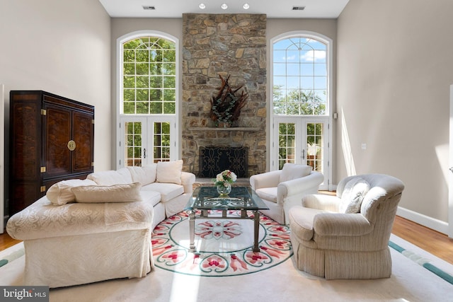 living area featuring french doors, a towering ceiling, wood finished floors, and a healthy amount of sunlight