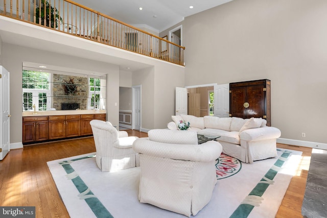 living area featuring wood finished floors, recessed lighting, baseboards, and a high ceiling