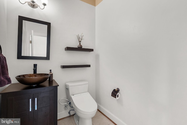 bathroom featuring baseboards, vanity, and toilet