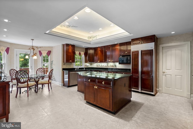 kitchen featuring built in appliances, dark countertops, a center island, recessed lighting, and a raised ceiling