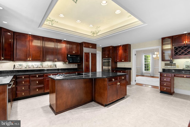 kitchen with a raised ceiling, recessed lighting, reddish brown cabinets, a kitchen island, and black appliances