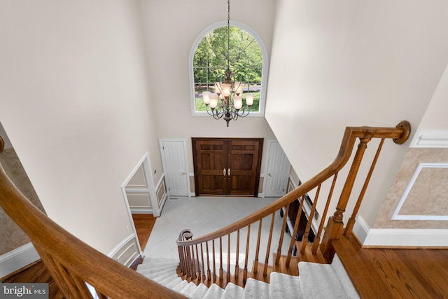 entrance foyer with stairs, a high ceiling, an inviting chandelier, and baseboards