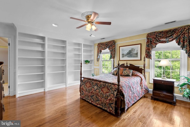 bedroom featuring crown molding, a ceiling fan, wood finished floors, and visible vents