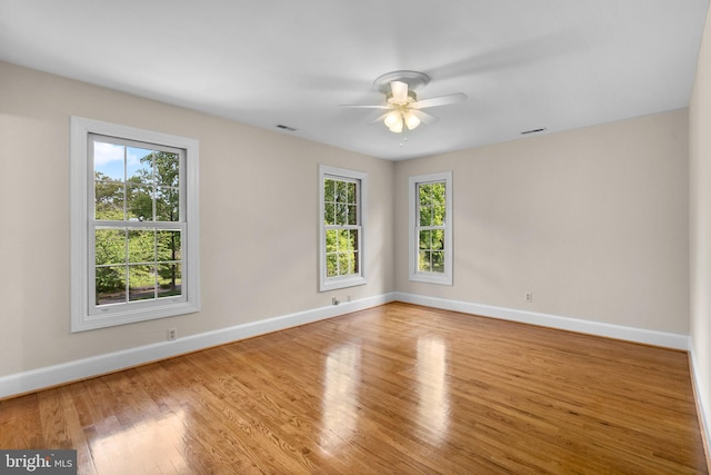 spare room featuring a ceiling fan, baseboards, a wealth of natural light, and wood finished floors